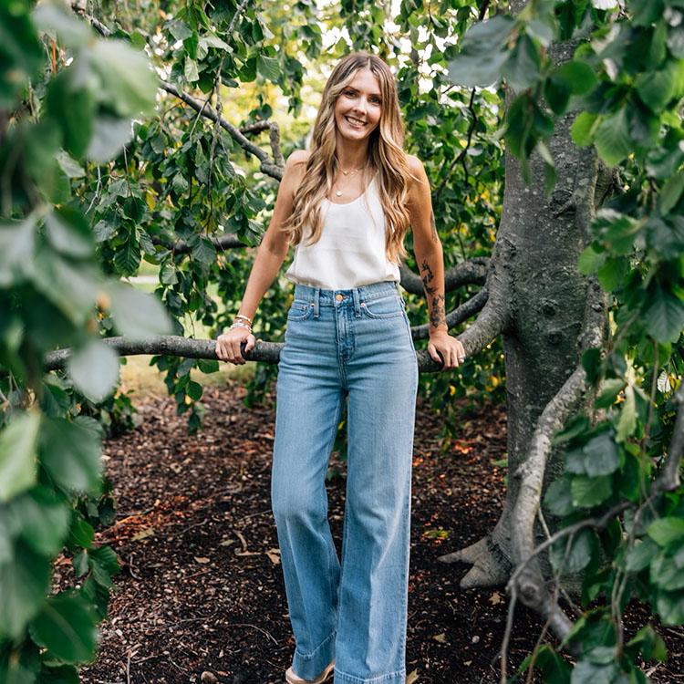 galina (owner of adriana grey esthetics) standing against tree and smiling